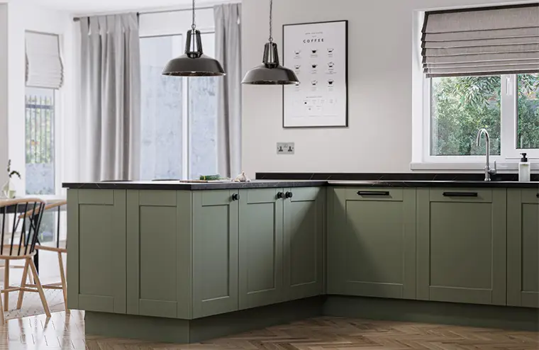 Reed green kitchen with dark marble worktops and parquet flooring.