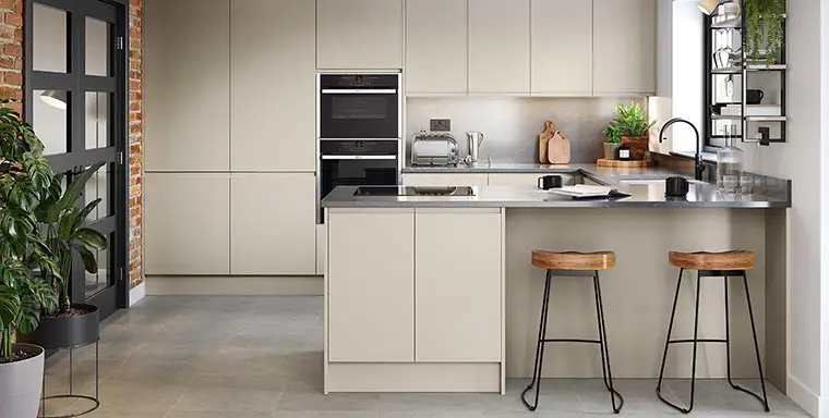 Cream j handle kitchen with grey quartz worktop and limestone flooring.